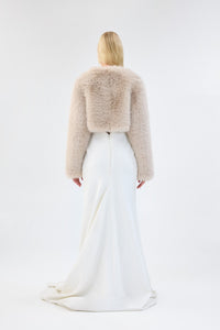 A model viewed from the front wearing a cream faux fur bridal cropped jacket over a white gown.