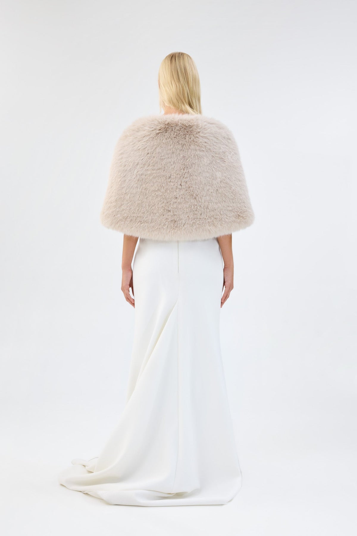 A model viewed from the back wearing a cream faux fur bridal wrap over a white gown.