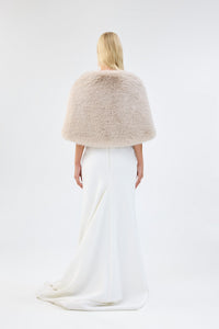 A model viewed from the back wearing a cream faux fur bridal wrap over a white gown.