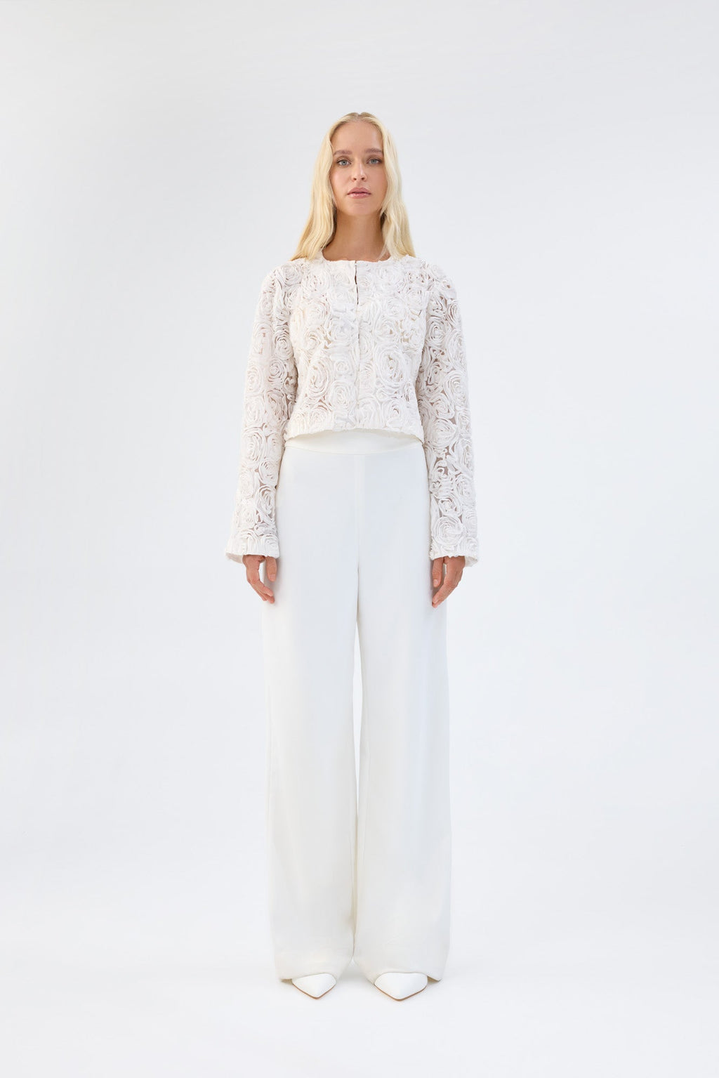 A model viewed from the front wearing a white floral textured cropped jacket.
