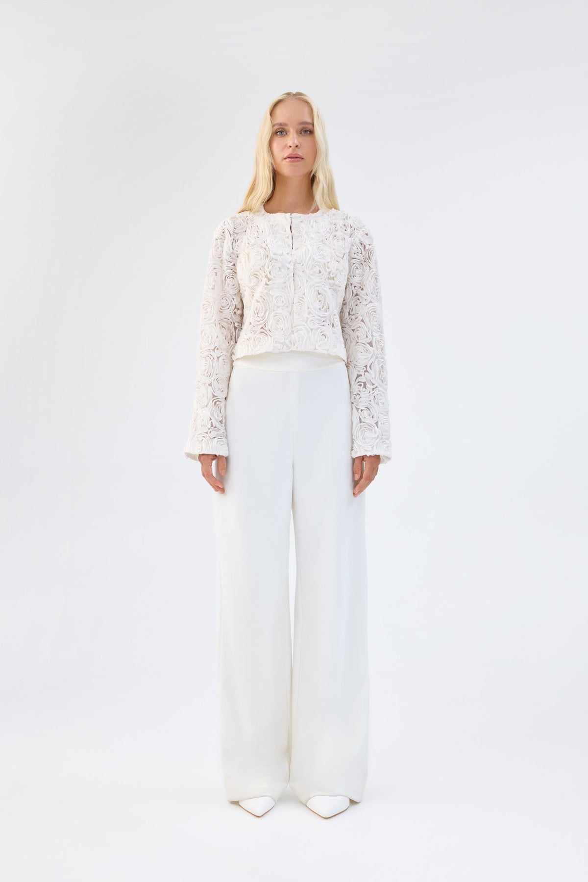 A model viewed from the front wearing a white floral textured cropped jacket.
