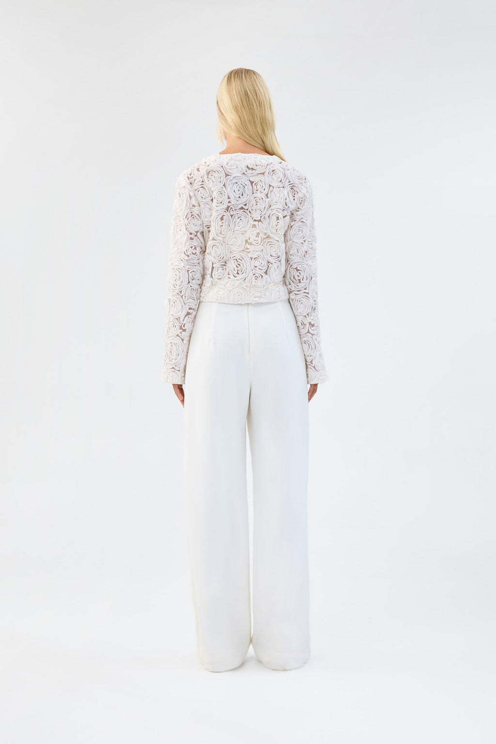 A model viewed from the back wearing a white floral textured cropped jacket.