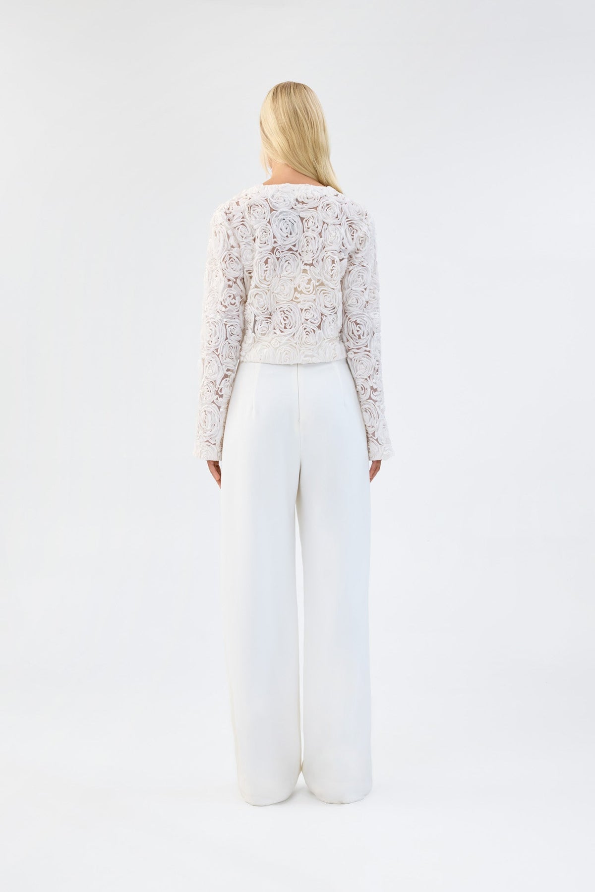A model viewed from the back wearing a white floral textured cropped jacket.