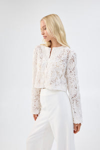 A model in three-quarter view wearing a white floral textured cropped jacket.