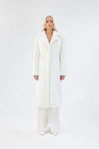 A model viewed from the front wearing a long white faux fur coat.