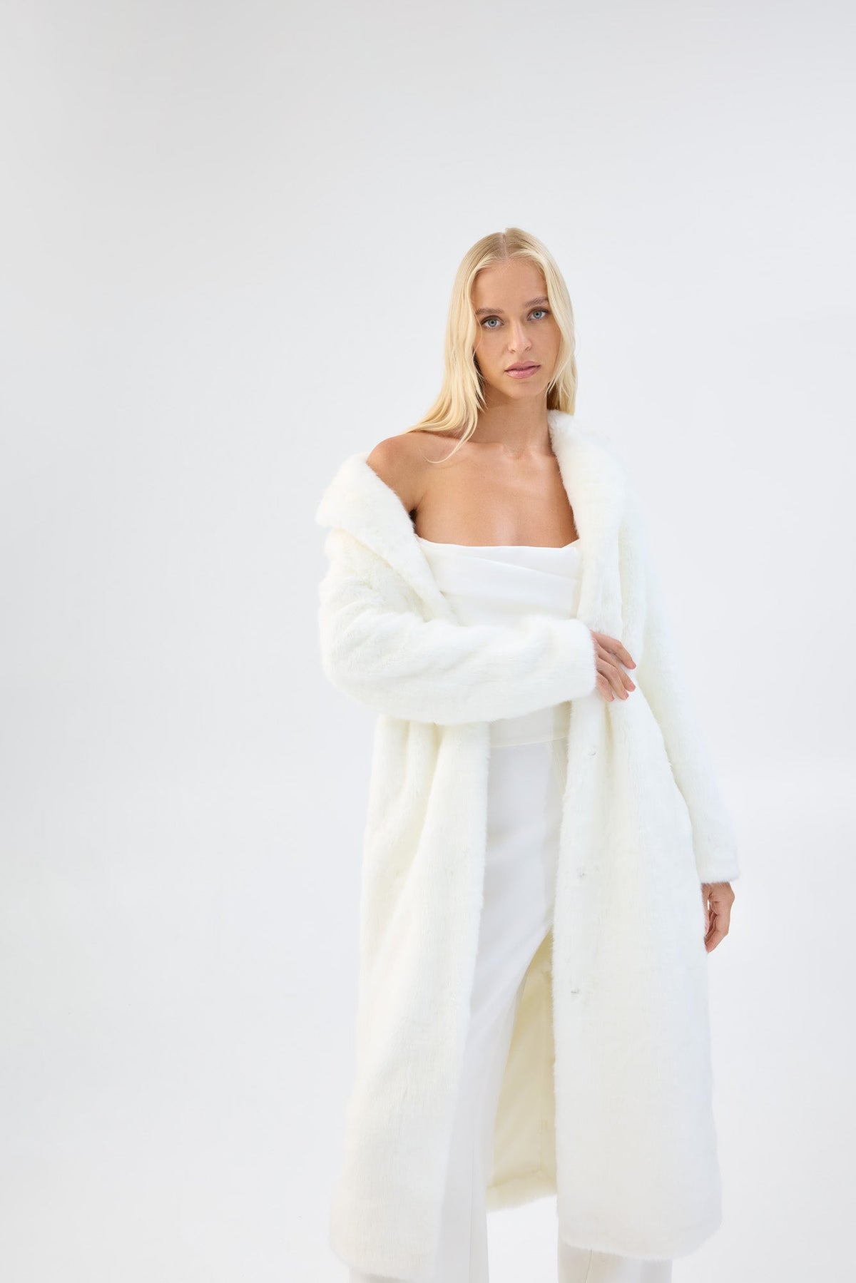A model in three-quarter view wearing a long white faux fur coat.
