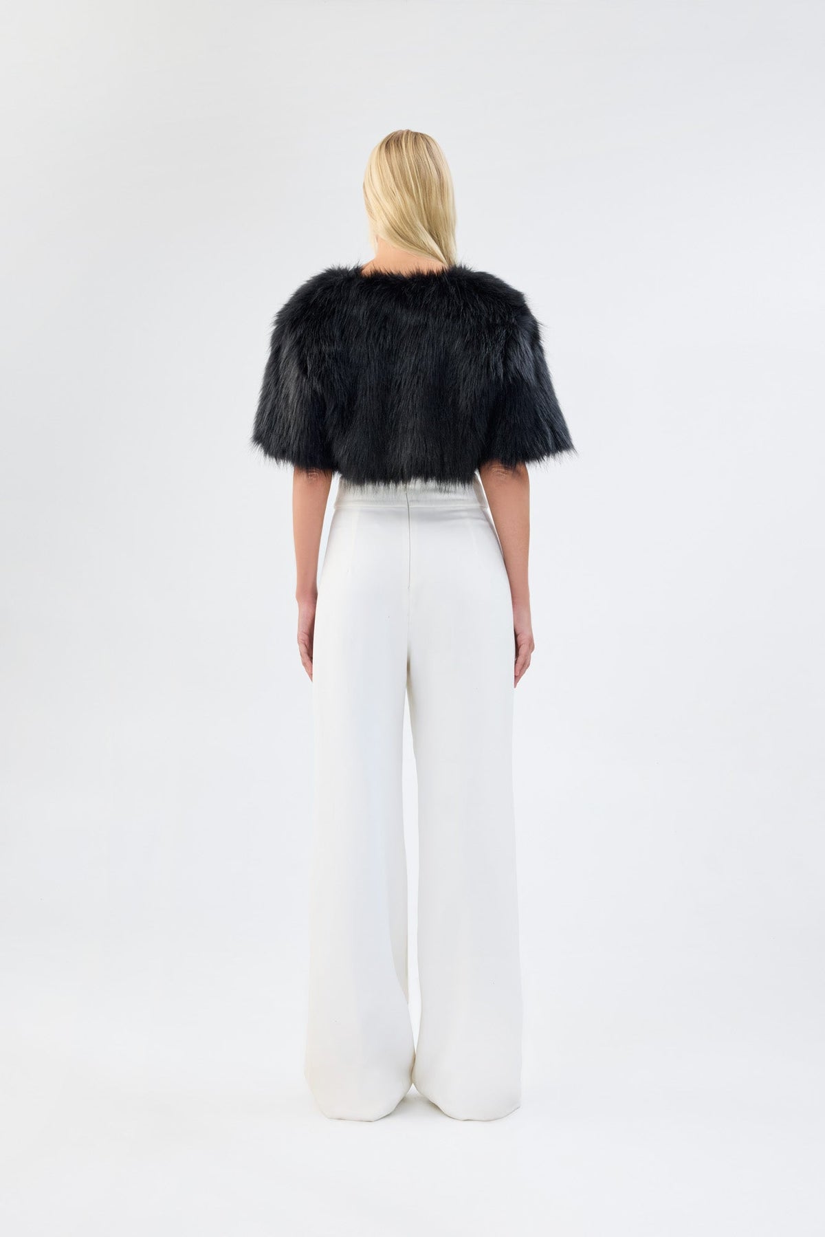 A model viewed from the back wearing a black faux fur bridal bolero.