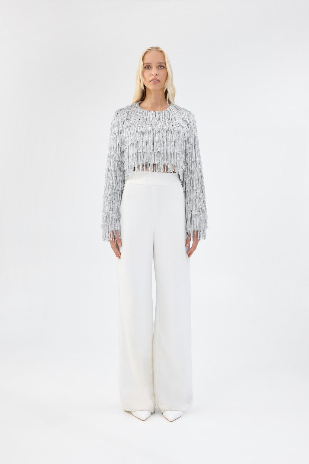 A model viewed from the front wearing a cropped silver fringe jacket.