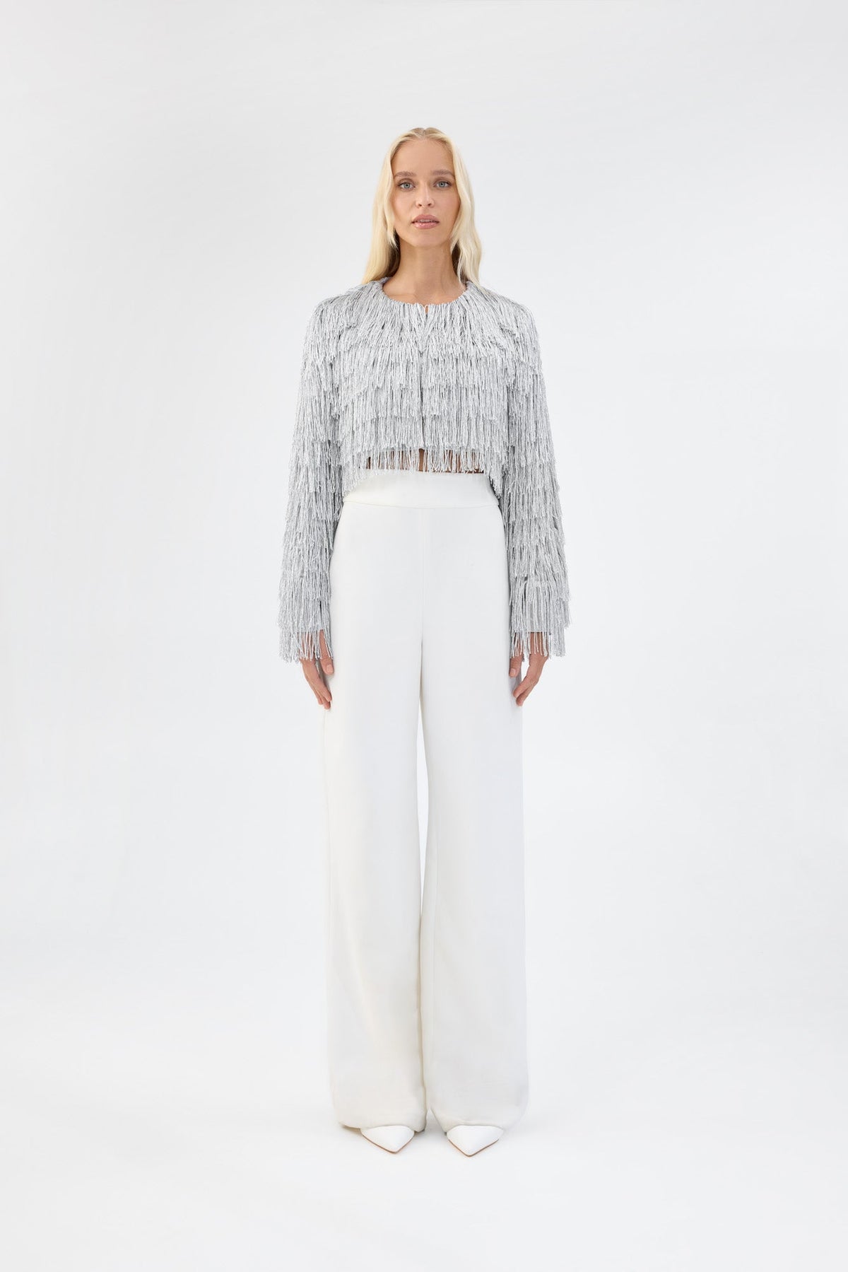 A model viewed from the front wearing a cropped silver fringe jacket.