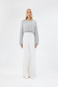 A model viewed from the front wearing a cropped silver fringe jacket.