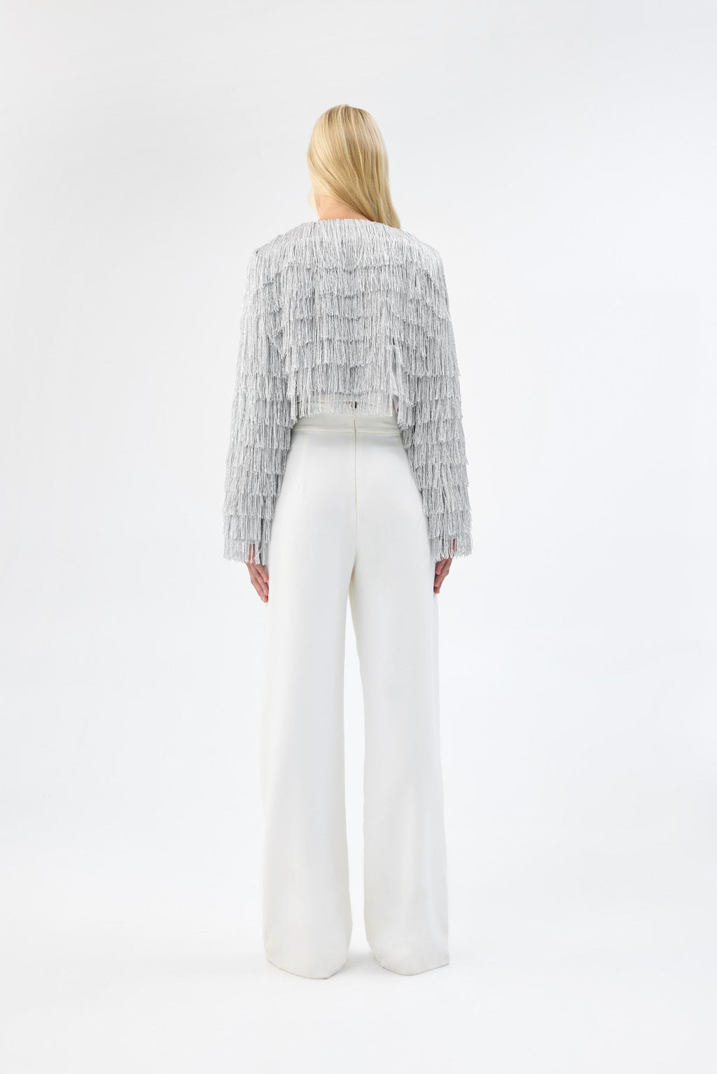 A model viewed from the back wearing a cropped silver fringe jacket.