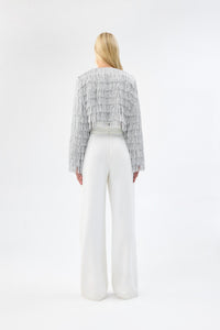 A model viewed from the back wearing a cropped silver fringe jacket.