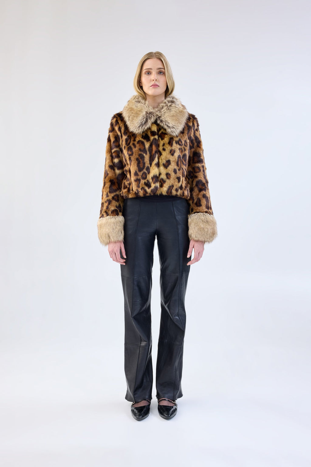 A model viewed from the front wearing a leopard print faux fur jacket with contrasting collar and cuffs.