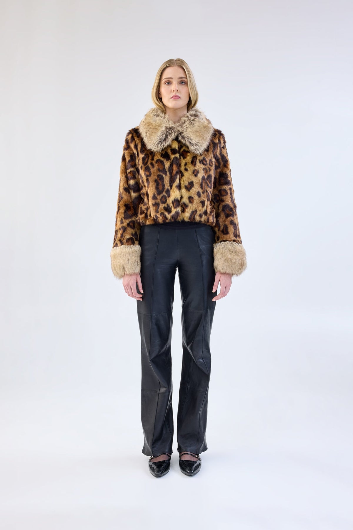 A model viewed from the front wearing a leopard print faux fur jacket with contrasting collar and cuffs.