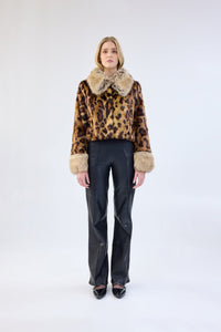 A model viewed from the front wearing a leopard print faux fur jacket with contrasting collar and cuffs.