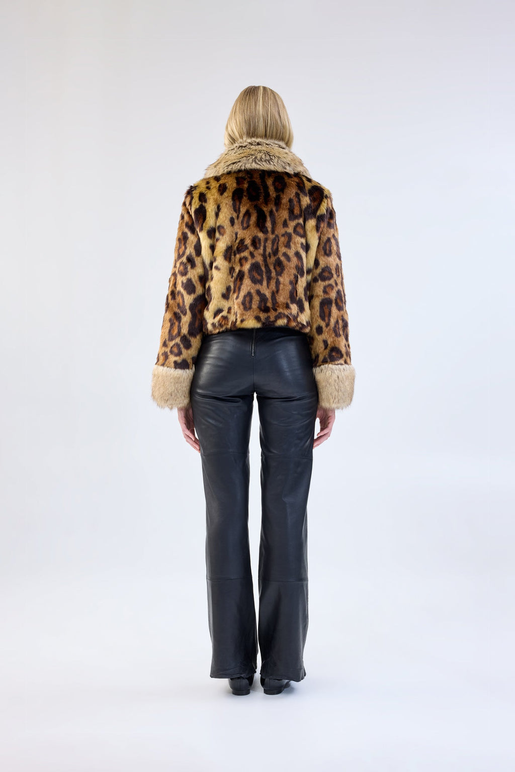A model viewed from the back wearing a leopard print faux fur jacket.