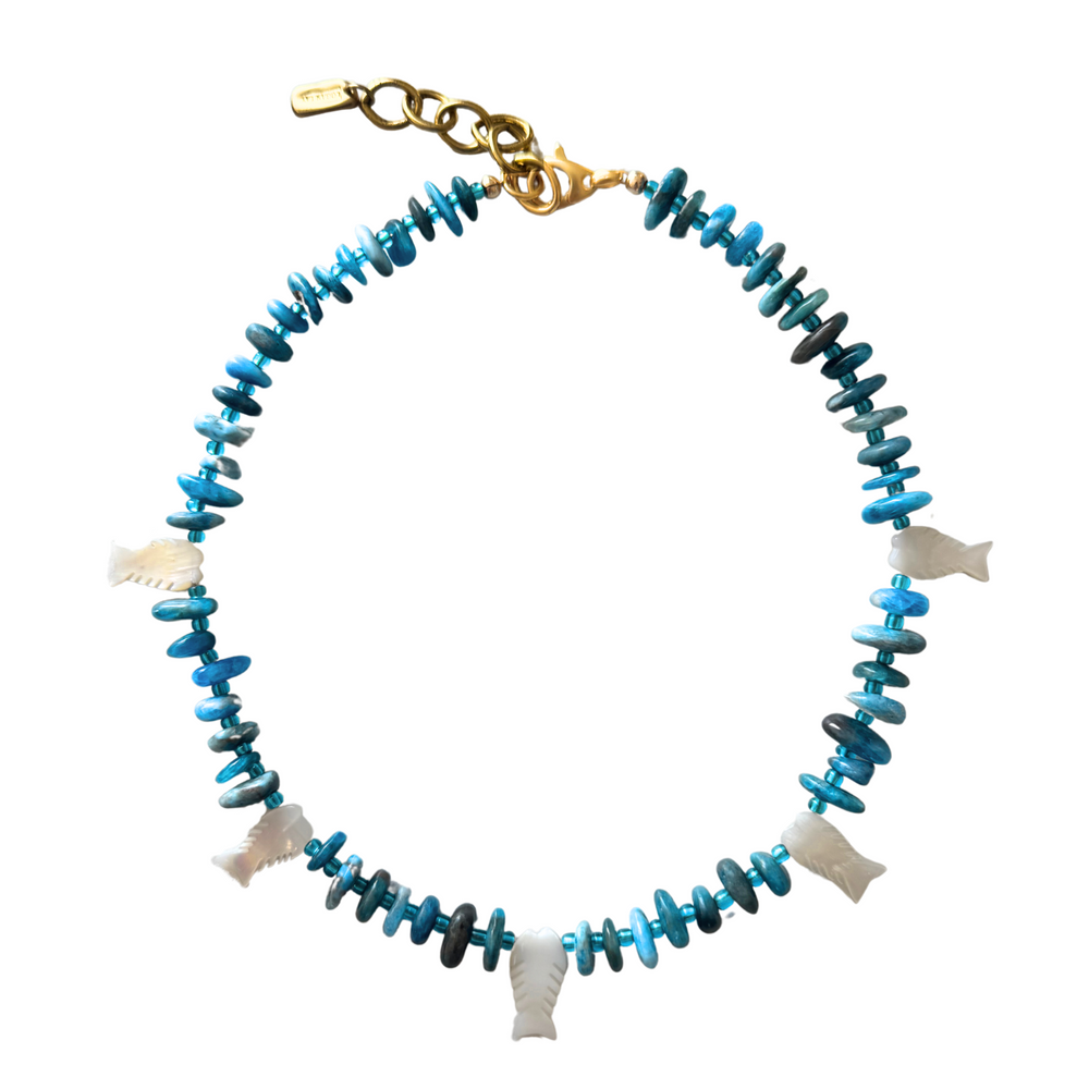 Top-down view of Scaly Blue Fish necklace with blue chip beads and mother-of-pearl fish pendants on white background