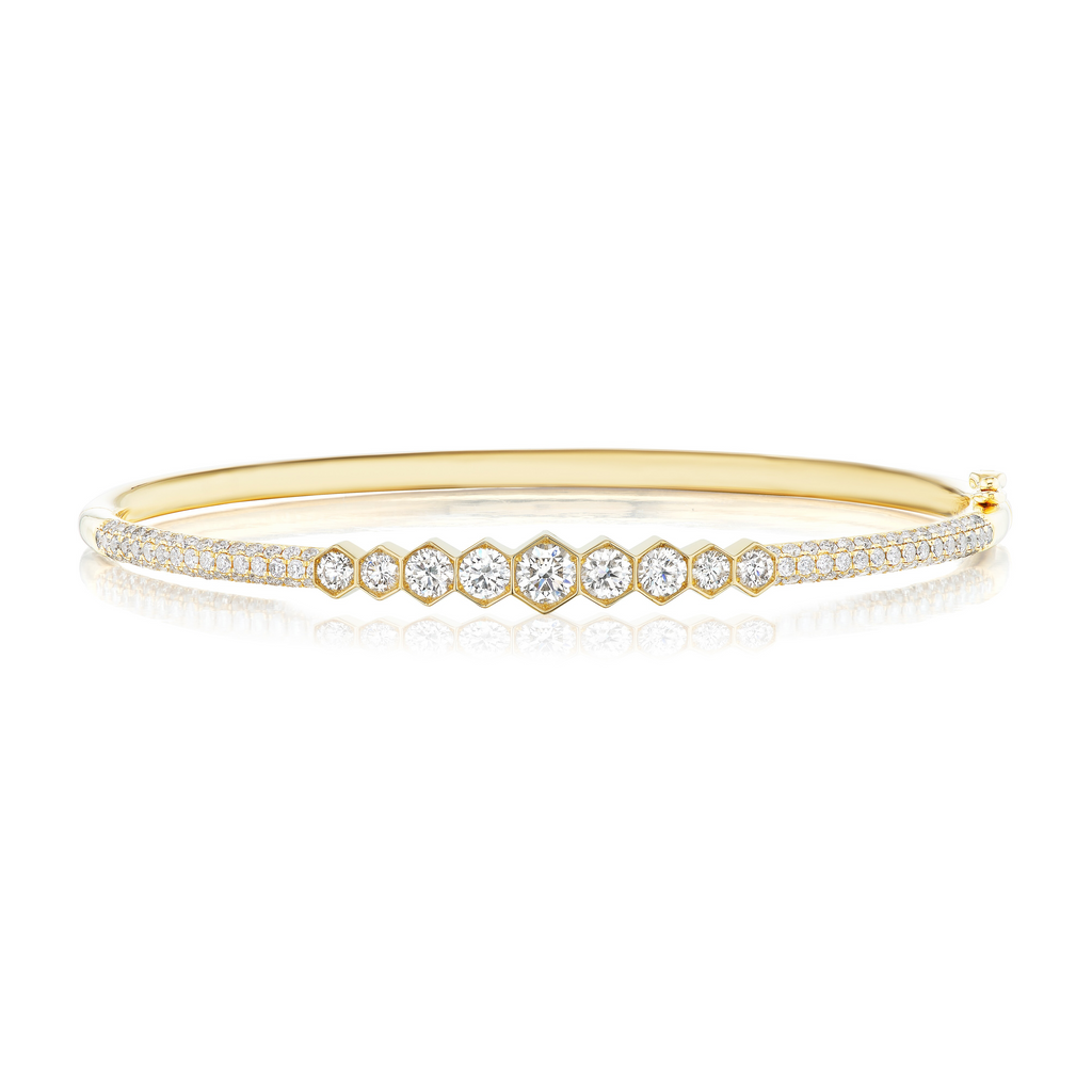 The Graduated Hexagon Bezel Set Diamond Pavé Bangle showcases a row of graduated SI clarity diamonds bezel set at the center, bordered by two pavé-set diamond rows on an elegant 18k gold band.