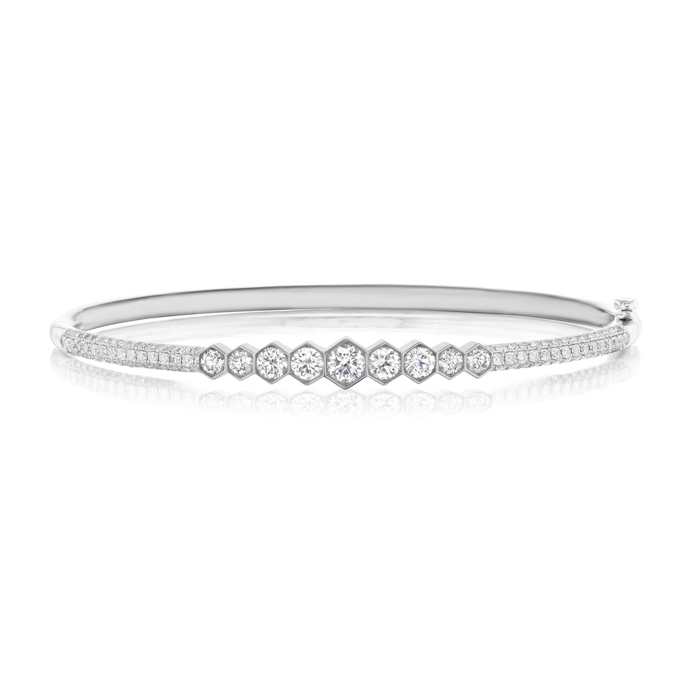 The Graduated Hexagon Bezel Set Diamond Pavé Bangle showcases SI clarity round and hexagonal center diamonds, framed by two slim rows of pavé-set diamonds along the silver band.