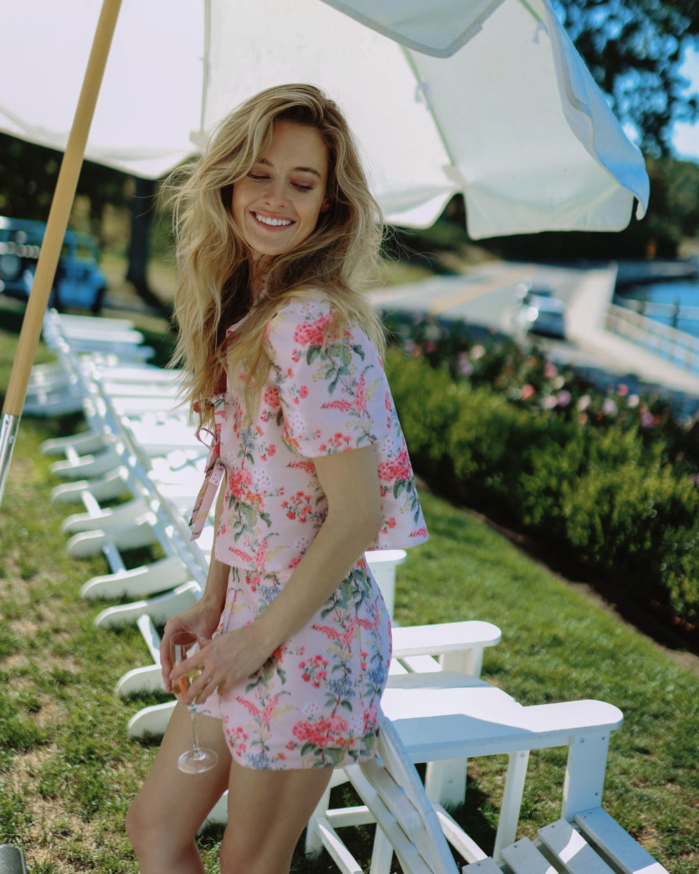 Side view of Cadence Top in Blush Floral showing puff sleeves front tie and cropped waist on model in sunny outdoor setting