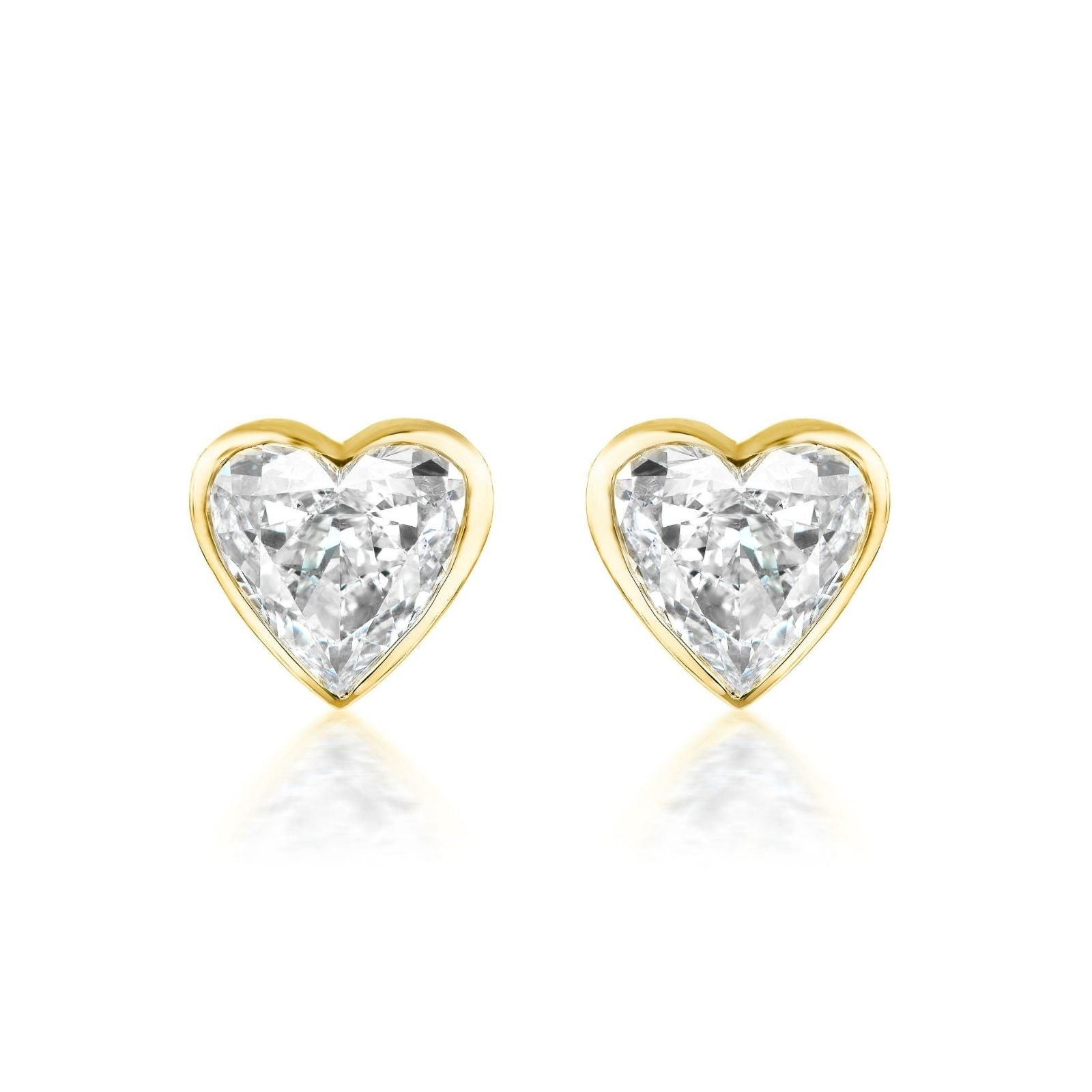 The Bezel Set Diamond Heart Studs showcase G color diamonds in a heart shape, set in 18k gold and displayed on a white background.