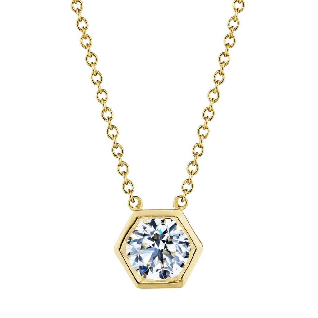 The Hexagon Bezel Set Round Brilliant Diamond Pendant features a gold chain and a hexagon pendant with a large, round, bezel-set diamond at its center—modern elegance inspired by the classic solitaire look.