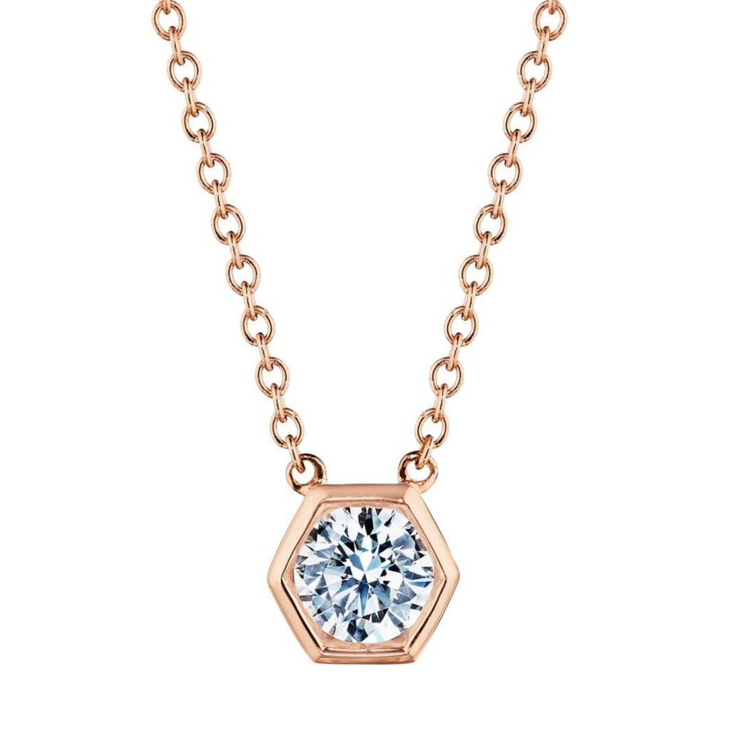 The Hexagon Bezel Set Round Brilliant Diamond Pendant showcases a round, sparkling diamond set in a rose gold hexagon bezel, hanging from a delicate rose gold chain.