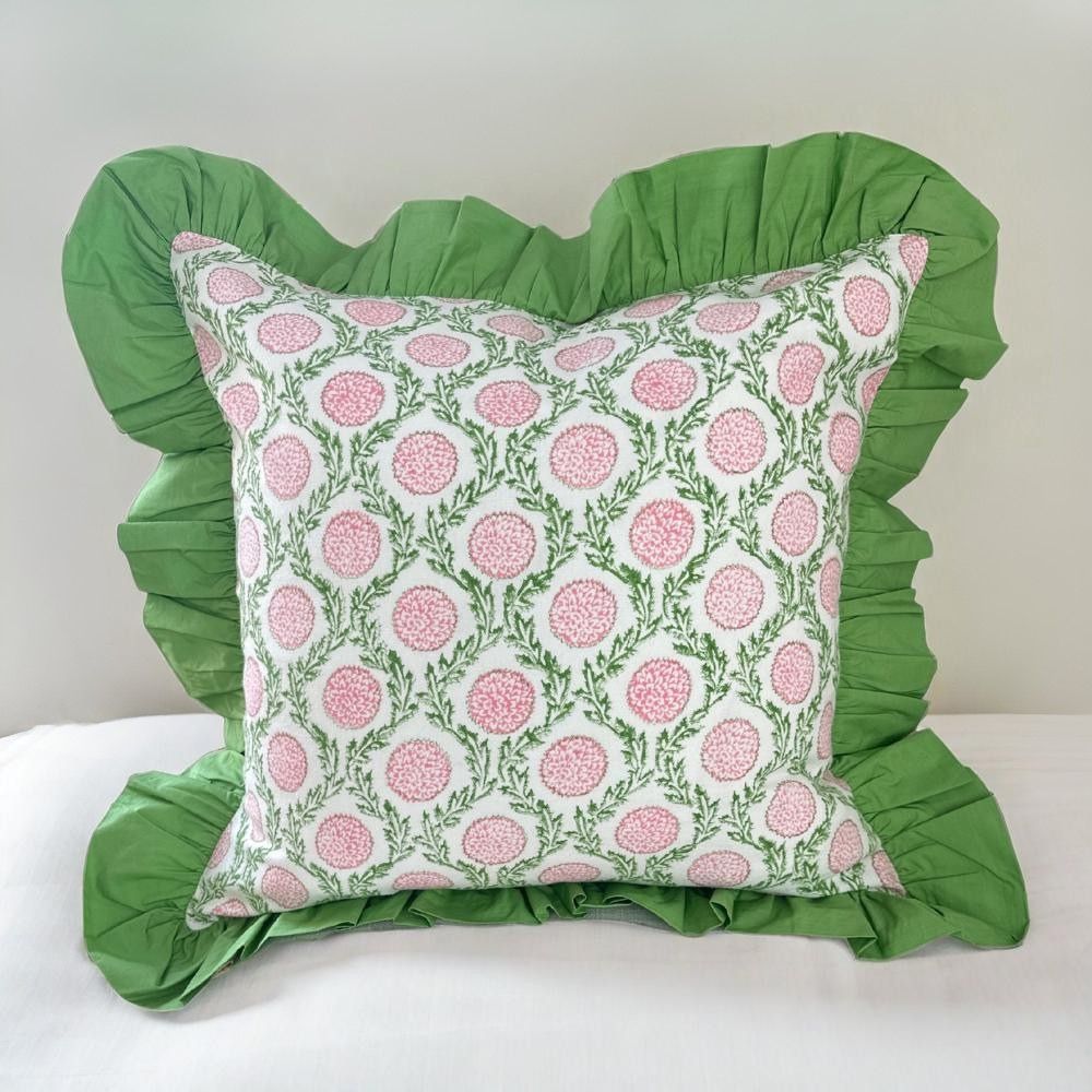 Decorative pillow with pink floral pattern and green ruffles on a white background