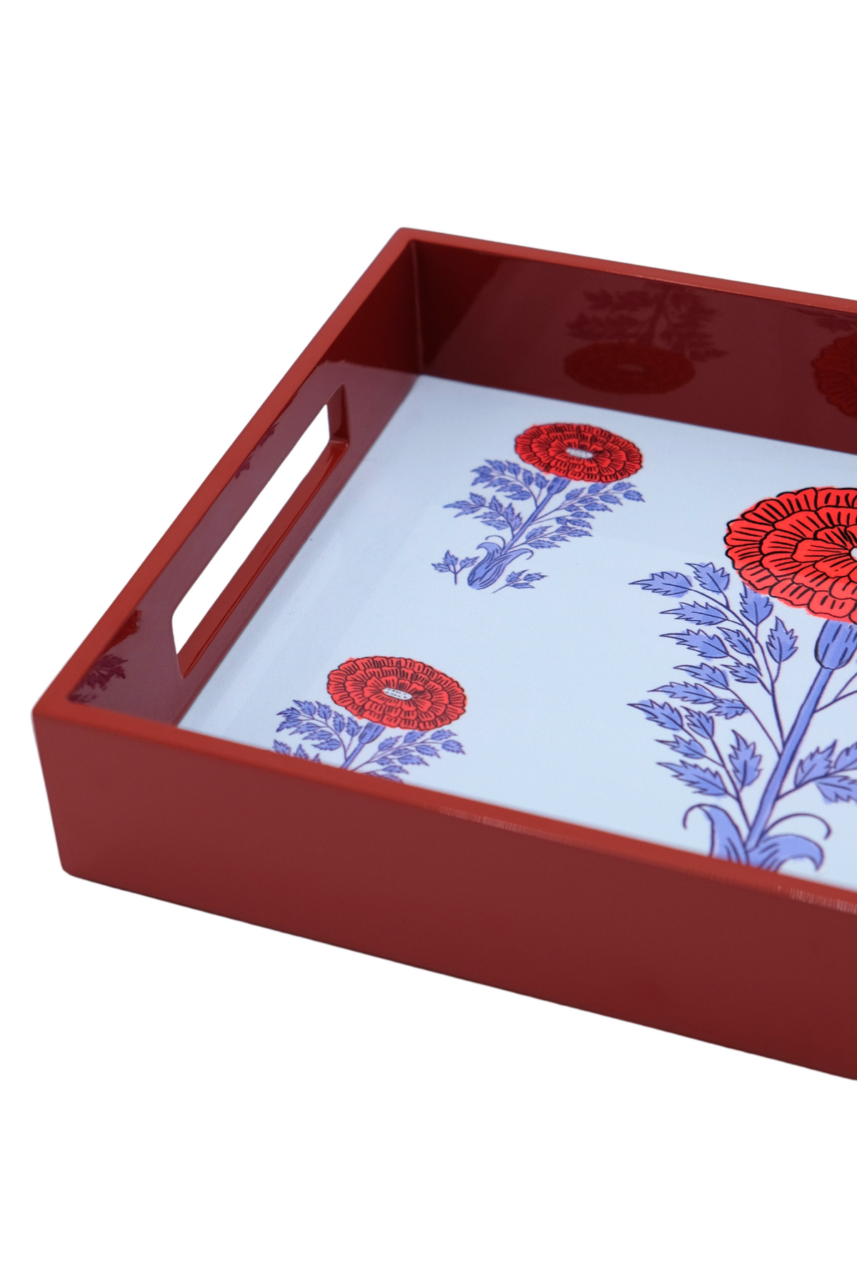 Angled view of Araminta lacquerware rectangular tray with glossy red sides, cutout handle, and white interior with blue and red floral print