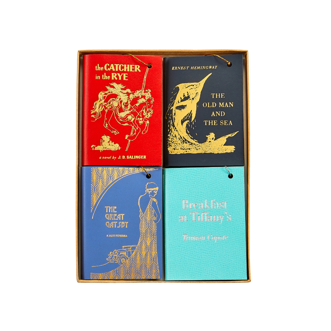 Four leather book ornaments featuring Catcher in the Rye, Old Man and the Sea, Great Gatsby, and Breakfast at Tiffany’s