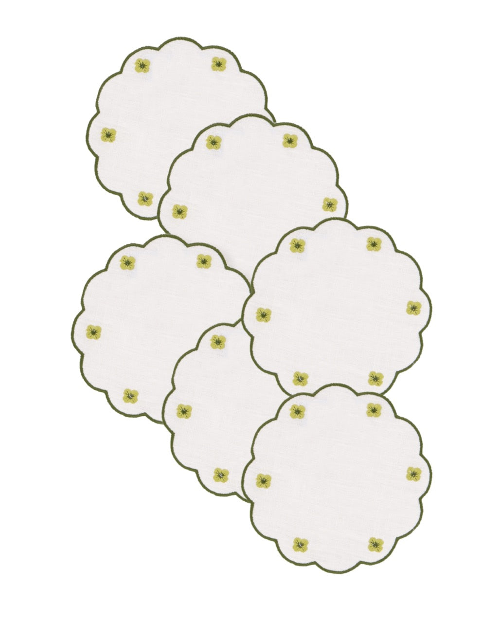 Top view of six white linen coasters showcasing scalloped edges and small green embroidered floral motifs