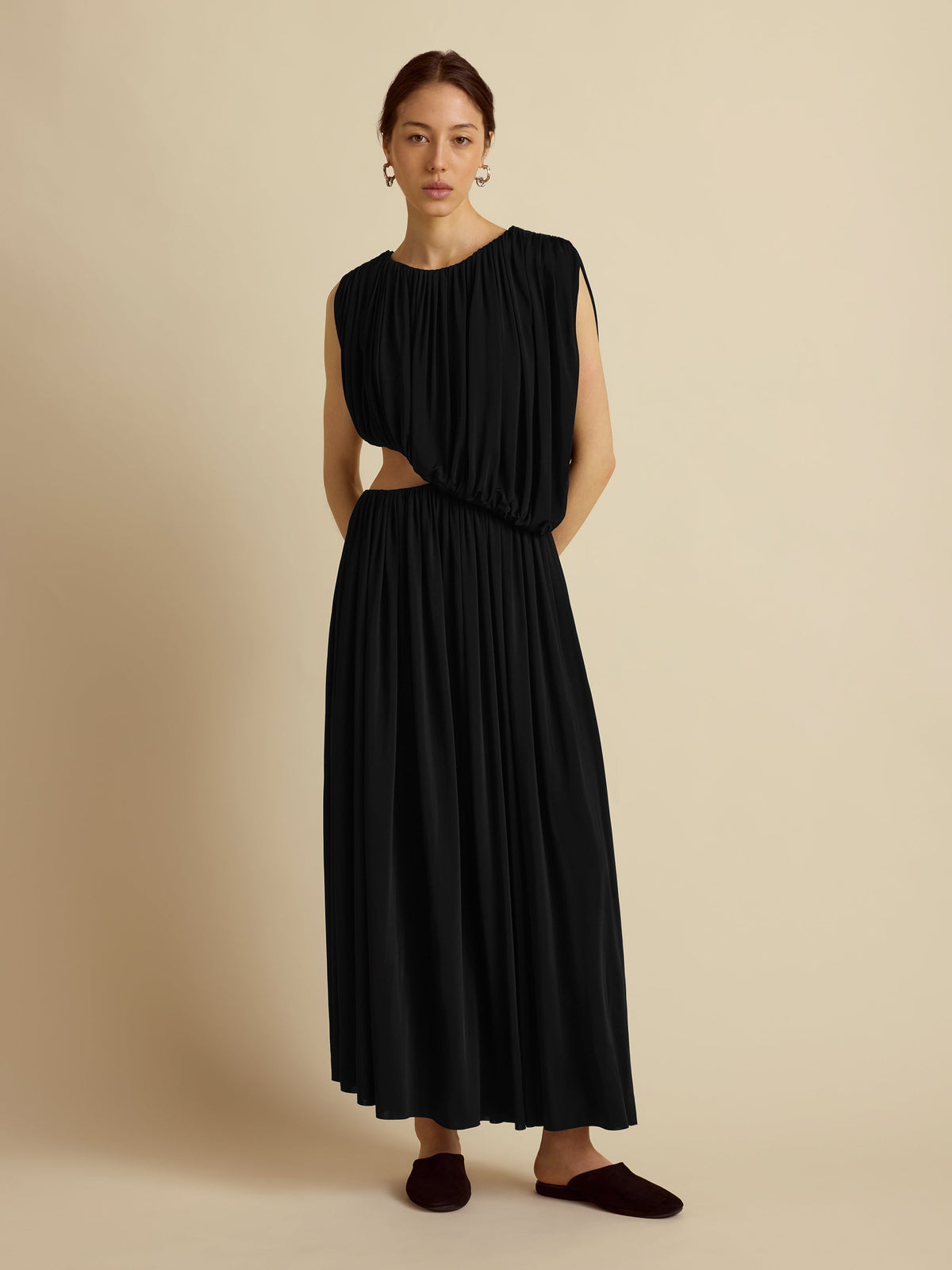 Front view of Draped Jersey Dress in black showcasing gathered draping, waist cutout, and ankle-length skirt on beige background