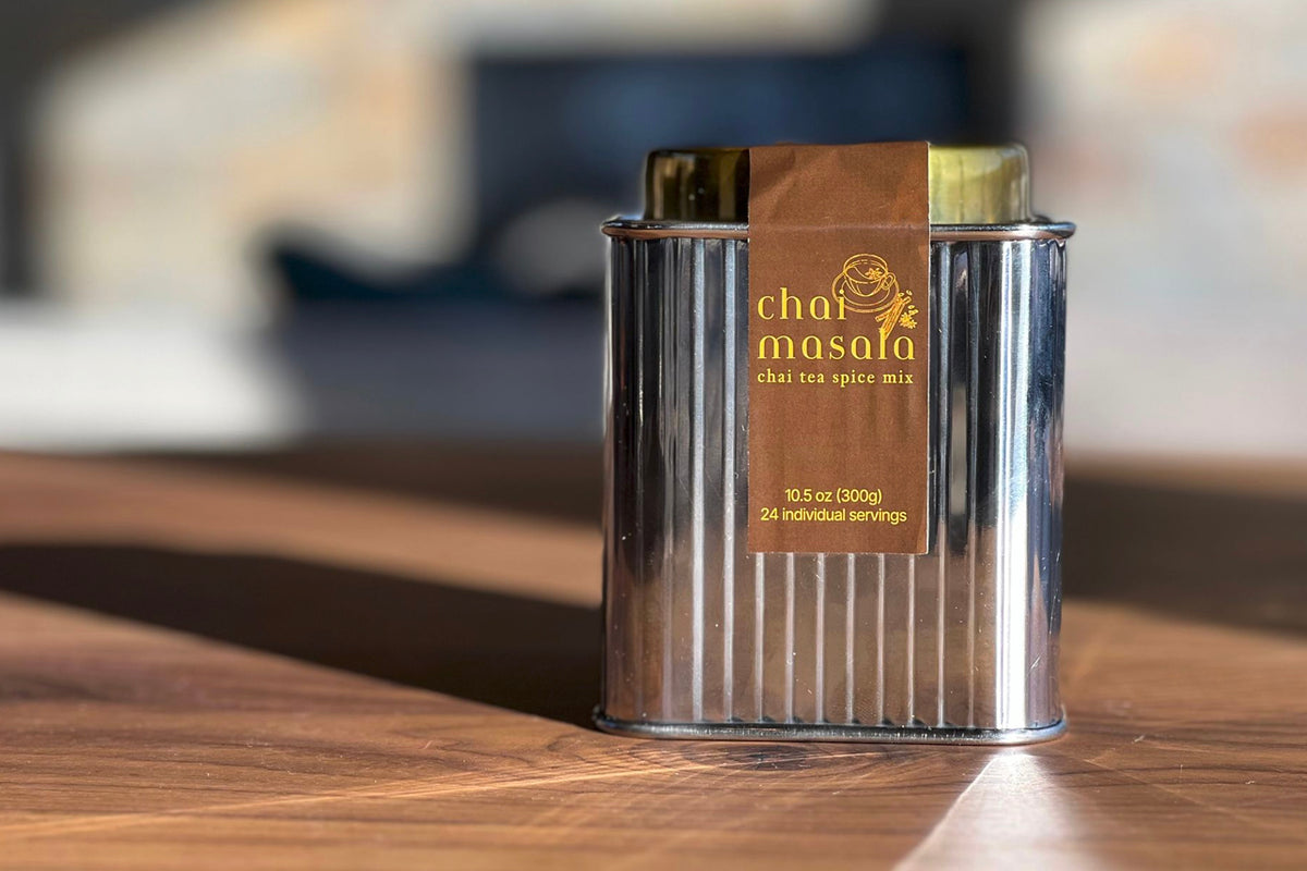Front view of Chai Masala tea spice mix tin with brown label ‘chai masala’ and ‘24 servings’ on wooden table