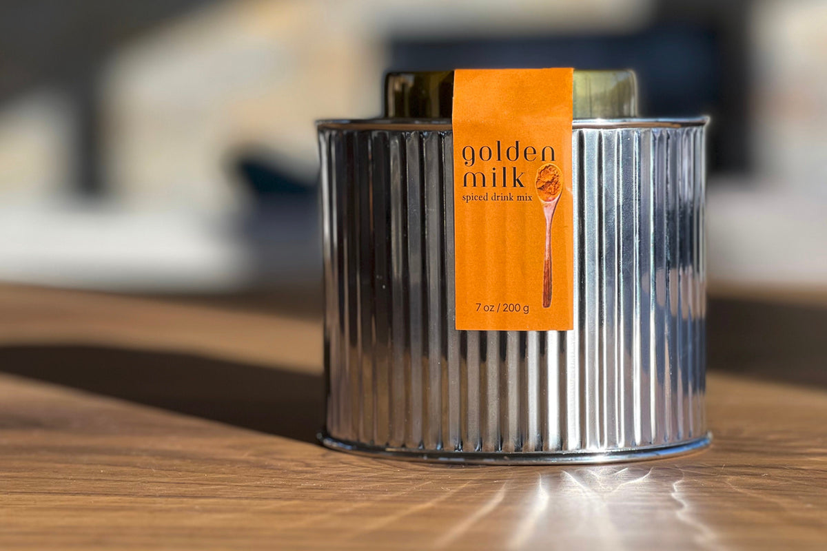 Front view of Golden Milk Spice Mix showcasing its ribbed metal tin marked 7 oz/200 g on a wooden table