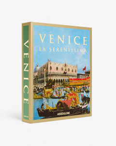 Venice: La Serenissima by Assouline: Three-quarter view of the closed clamshell box. The box front displays a full-color Canaletto-style painting of the Piazzetta and Doge's Palace with festive gondolas and barges in the foreground. VENICE in gold serif at top, LA SERENISSIMA below, ASSOULINE at the base. The green-accented spine reads VENICE vertically.