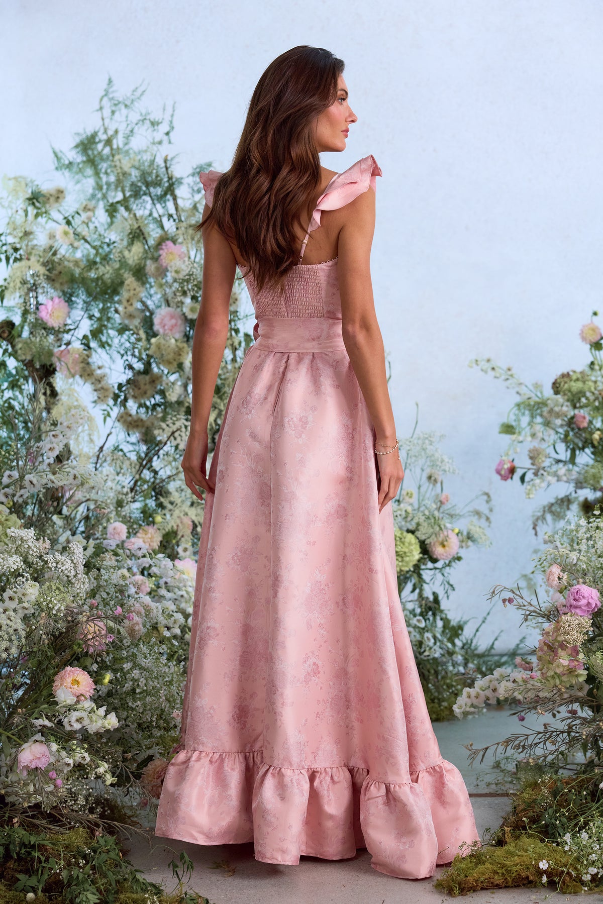 Back view of The Veronica Dress in Light Pink Windsor Brocade showcasing ruffled straps and floral brocade in flower garden