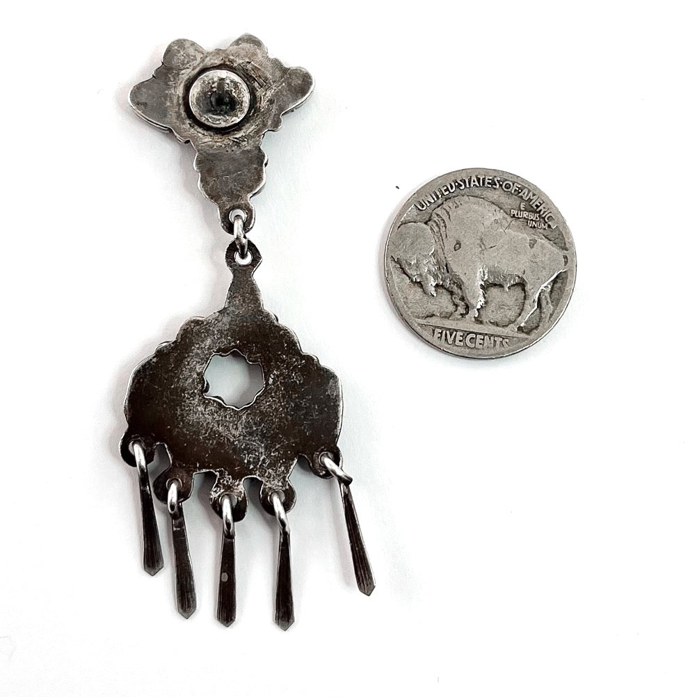 Close-up of vintage Zuni earrings showcasing dangling sterling silver and American turquoise with a coin for scale