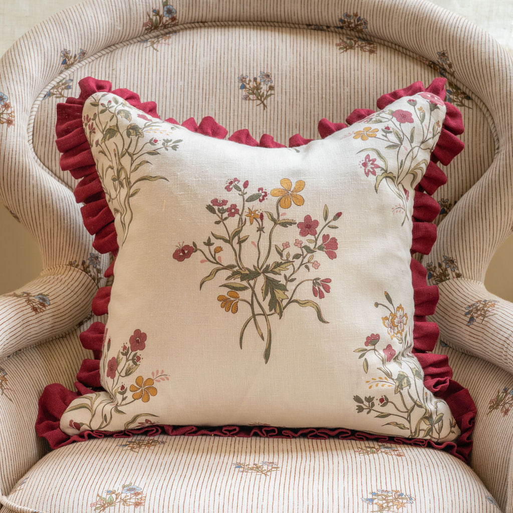 Front view of Flax & Field Flower Print Cushion in Scarlet showcasing floral linen print and scarlet frill on a striped chair
