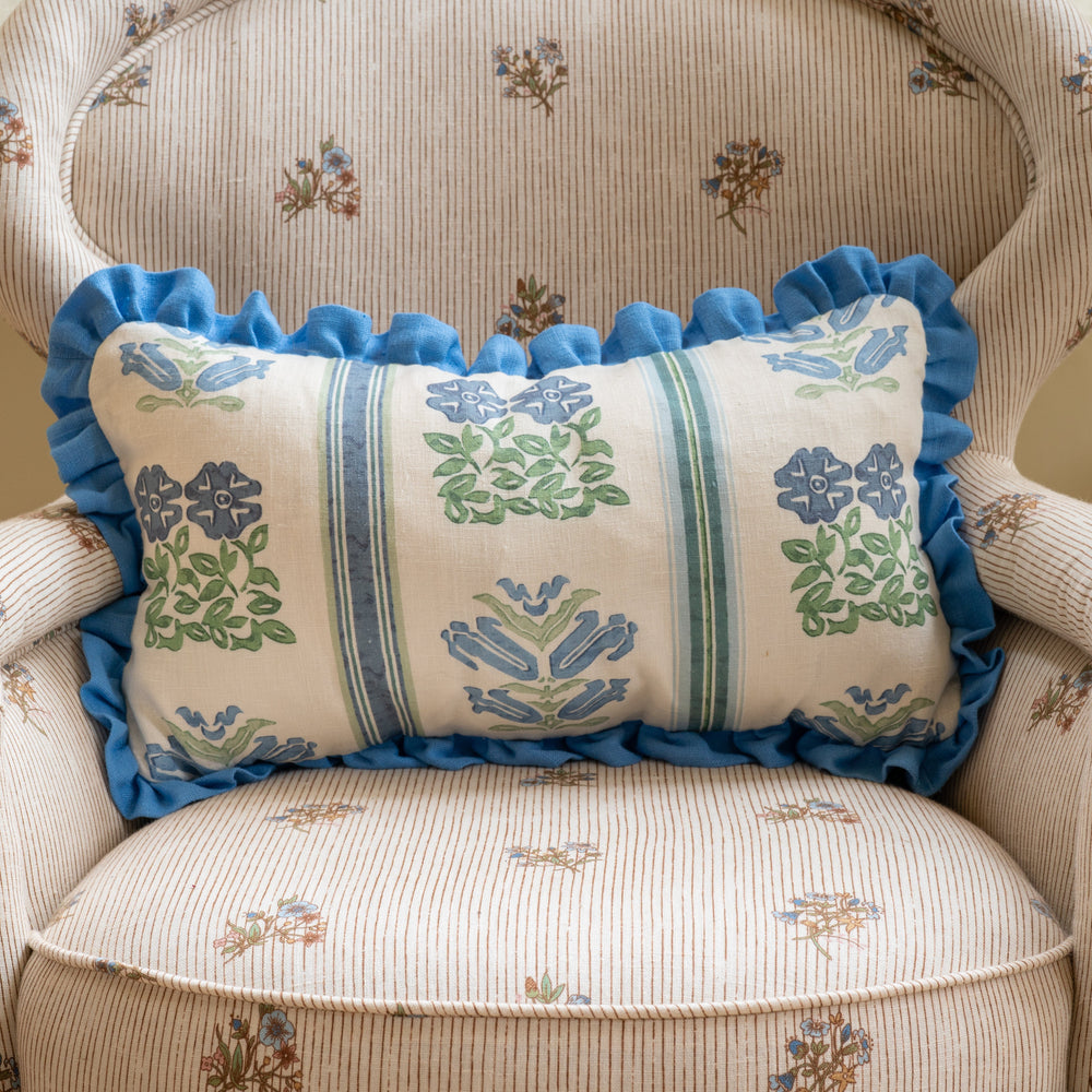 Front view of Folkloric Floral Print Cushion showcasing its Cornflower Blue frill and floral linen pattern on a striped upholstered chair
