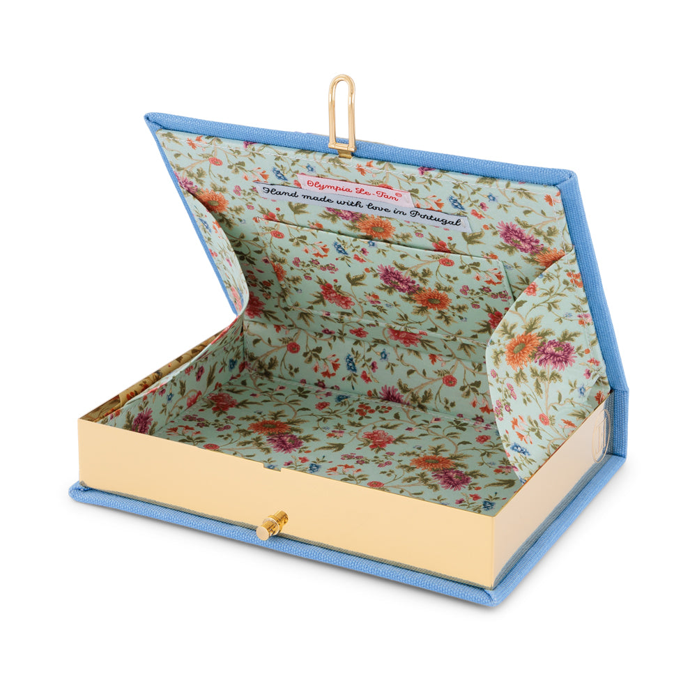 Open view of Provence in Blue Book Clutch showcasing floral fabric lined interior and brass frame on white background