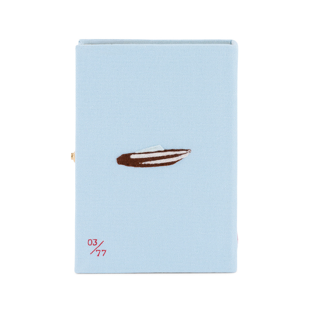 Back view of Lake Como Book Clutch in blue fabric, embroidered boat motif, red 03/77 numbering and gold clasp on white