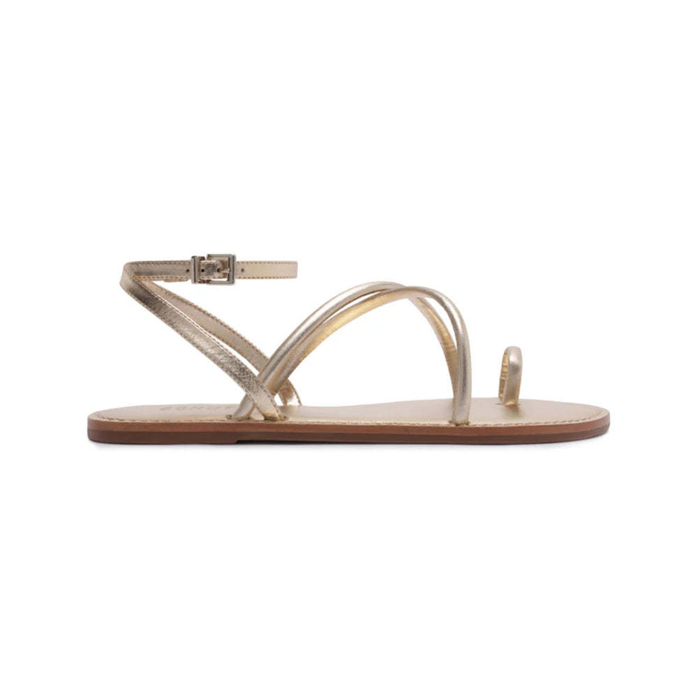 Side view of Valeria sandal in platinum showcasing asymmetrical metallic straps, toe loop, ankle buckle, and flat sole on white background