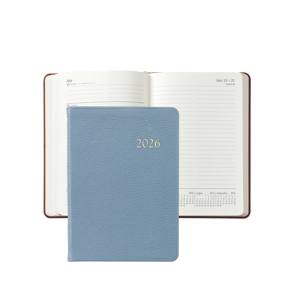 Front view of 2026 Weekly Notebook in slate blue pebble leather with gold embossed 2026 and open weekly pages visible