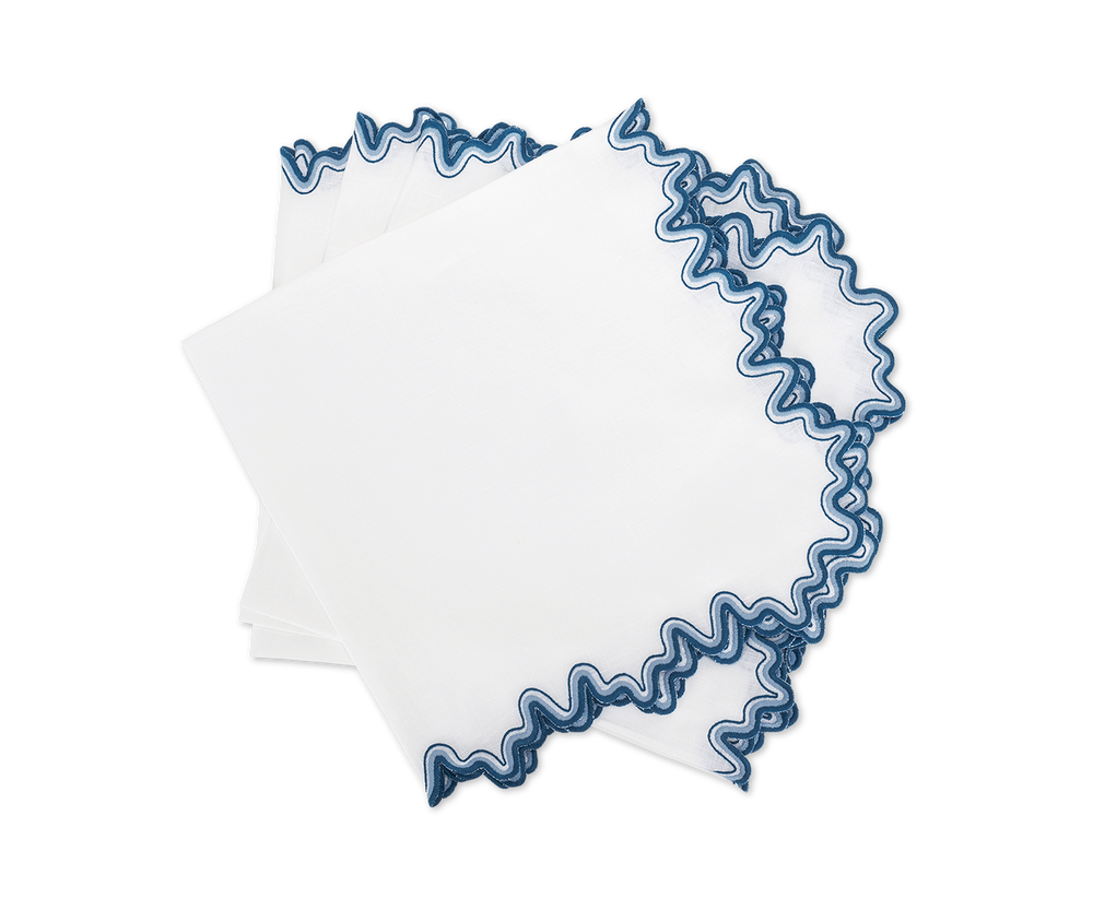 Top-down view of Wave linen napkins, set of 4 showcasing blue wavy scalloped embroidered edges on white fabric