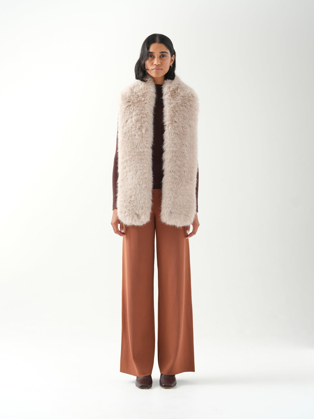 A model viewed from the front wearing a long cream faux fur scarf.