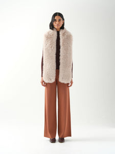 A model viewed from the front wearing a long cream faux fur scarf.