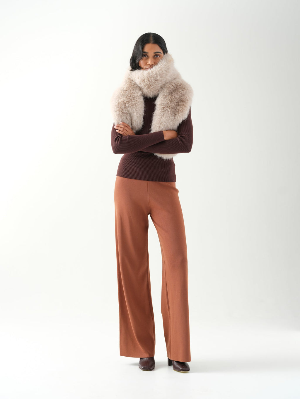 A model viewed from the front wearing a cream faux fur scarf wrapped around the neck.