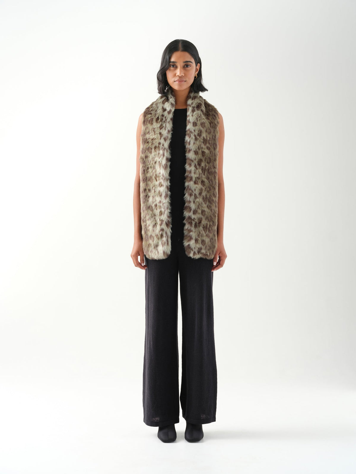 A model viewed from the front wearing a long green leopard  patterned faux fur scarf.