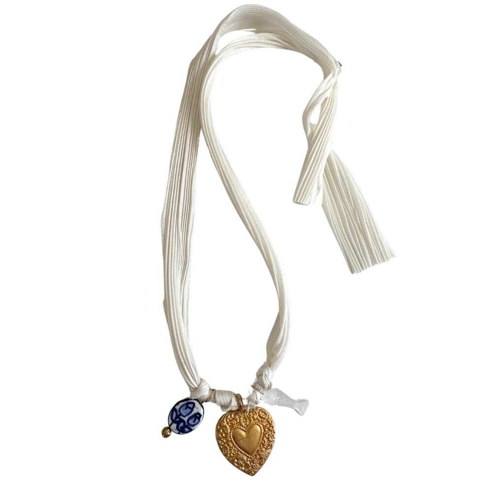 Front view of White Ribbon Charm Necklace showcasing white silk ribbon with gold heart, blue floral and clear fish charms