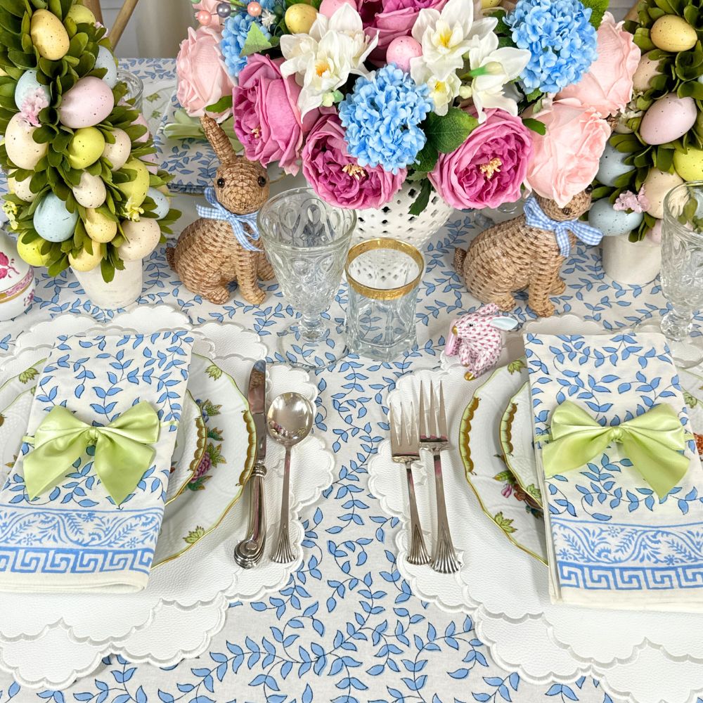Easter-themed table setting with floral arrangements, bunny decorations, and colorful eggs.